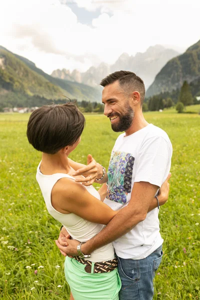 Coppia felice si abbraccia in un paesaggio montano, circondata dalla natura.