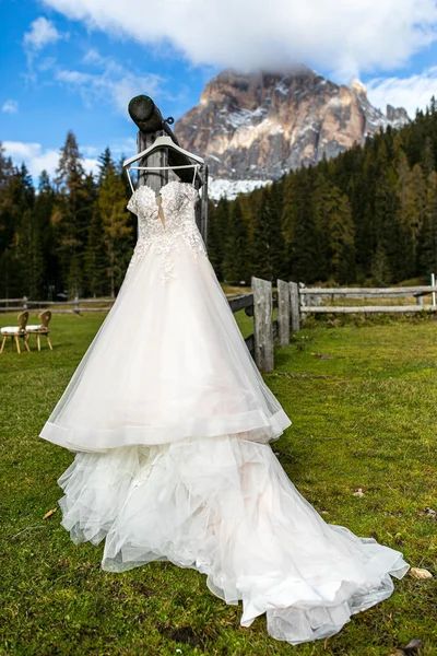 Abito da sposa appeso in un ambiente naturale con montagne sullo sfondo.