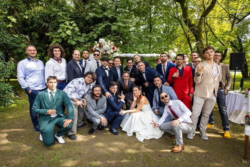 Gruppo di invitati sorridenti in giardino di Villa Luppis durante un matrimonio, brindano e posano insieme.
