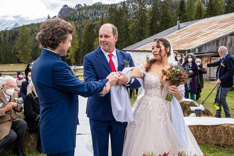 Sposi durante la cerimonia all'aperto, scambio di promesse in un rifugio a Cortina.